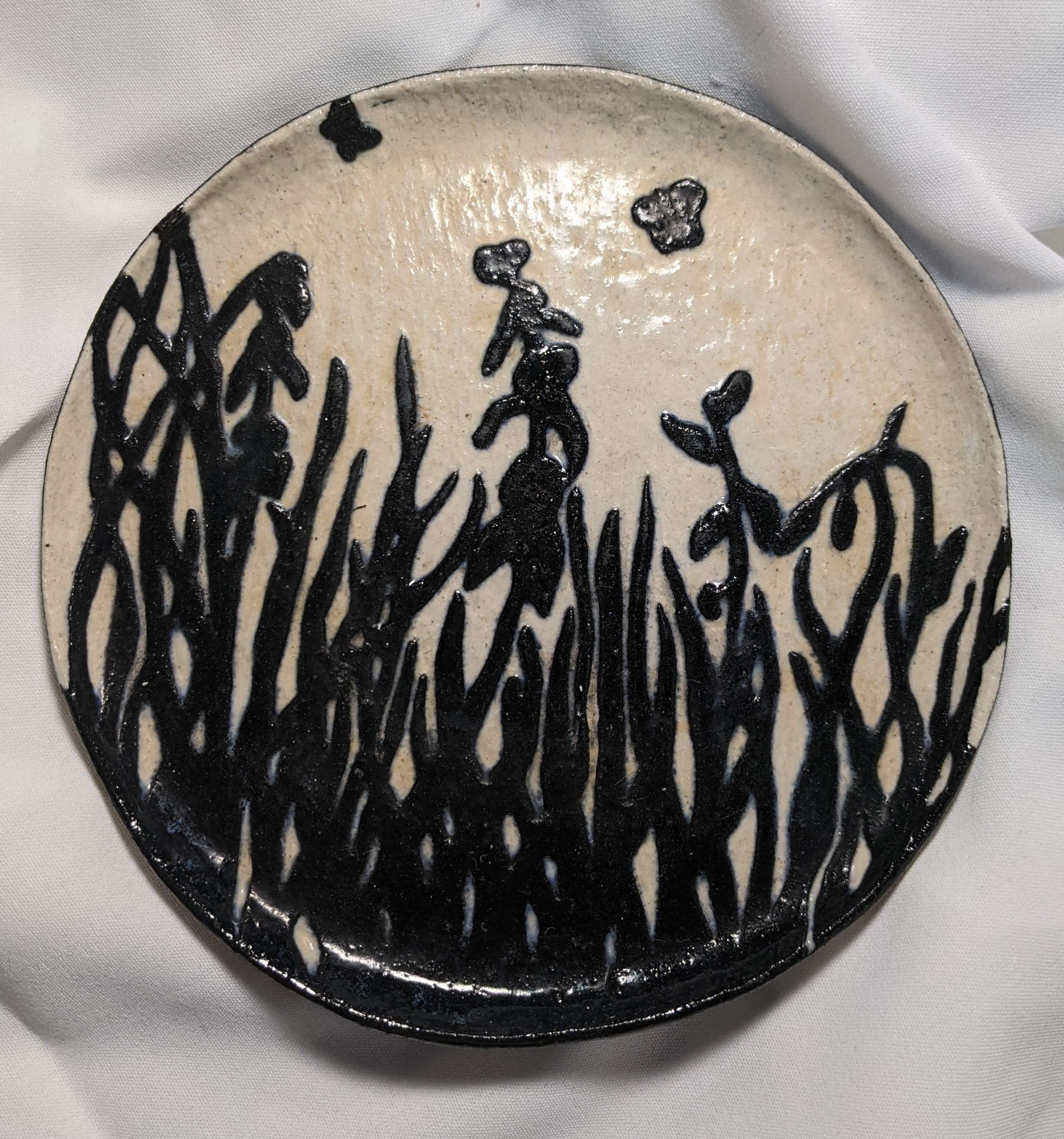 Circular resin artwork with black botanical silhouettes